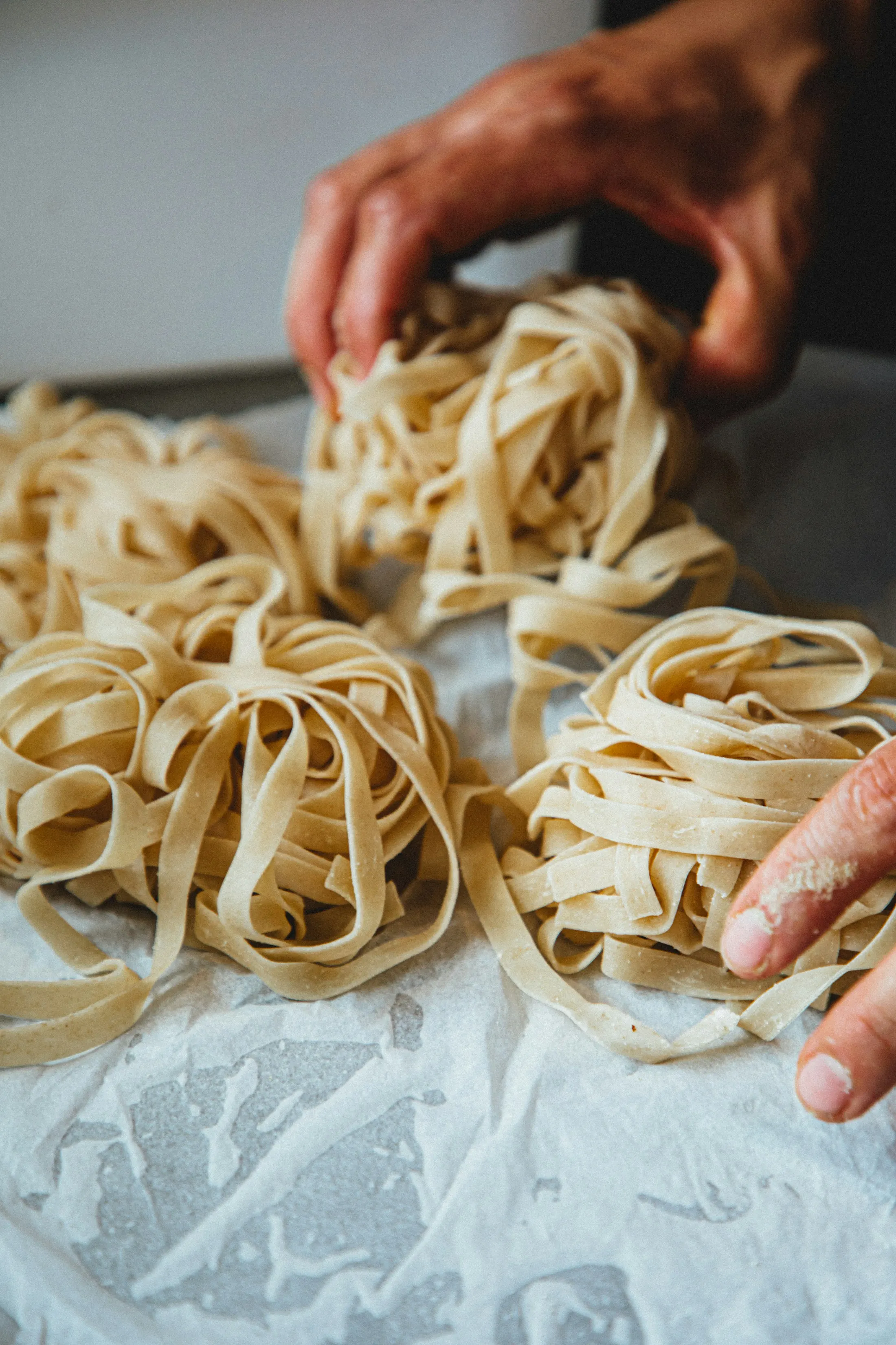 Hands lifting nests of fresh tagliatelle